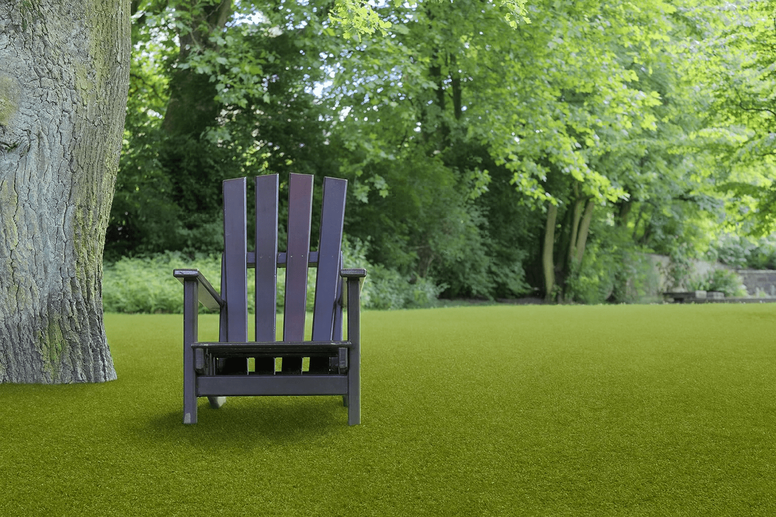 Gazon synthétique extérieur à l’aspect naturel, posé par un soliste moquetteur dans un jardin arboré