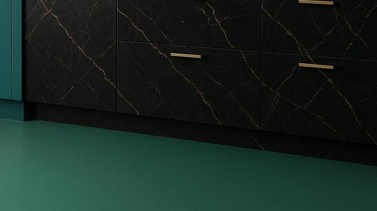 Sol en linoléum vert posé dans une cuisine moderne avec meubles noirs effet marbre et robinetterie dorée.