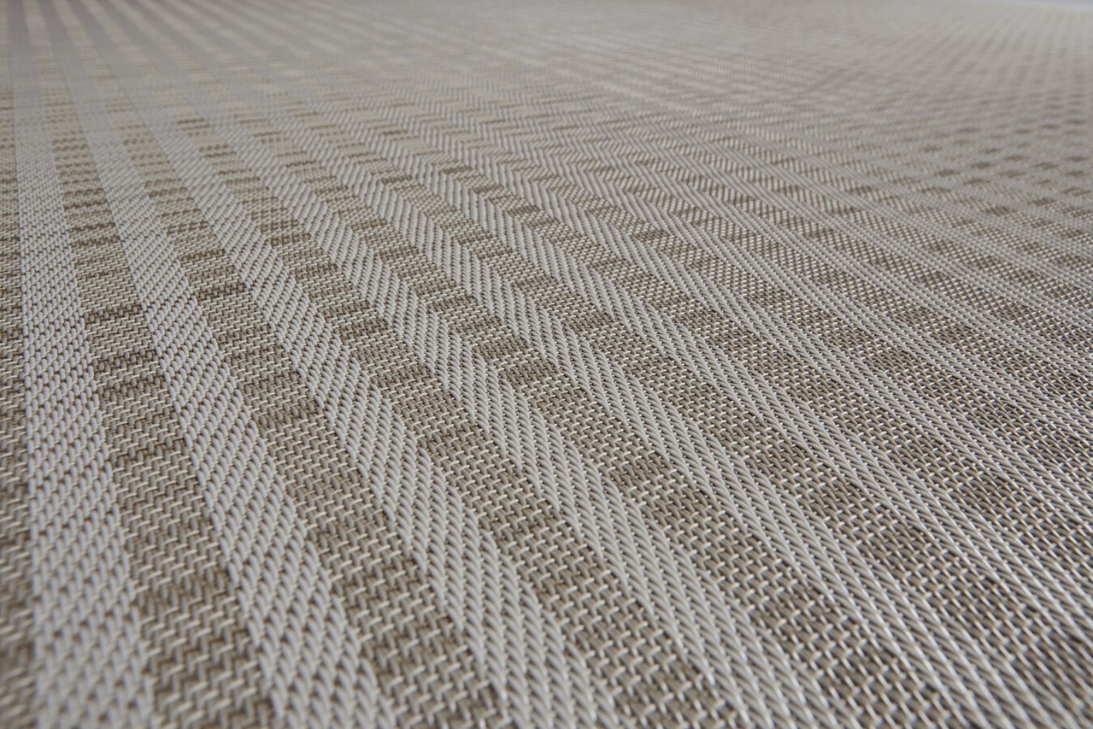 Gros plan d’un revêtement de sol Bolon à motif chevron, aux teintes beige et sable, mettant en valeur une texture tissée.