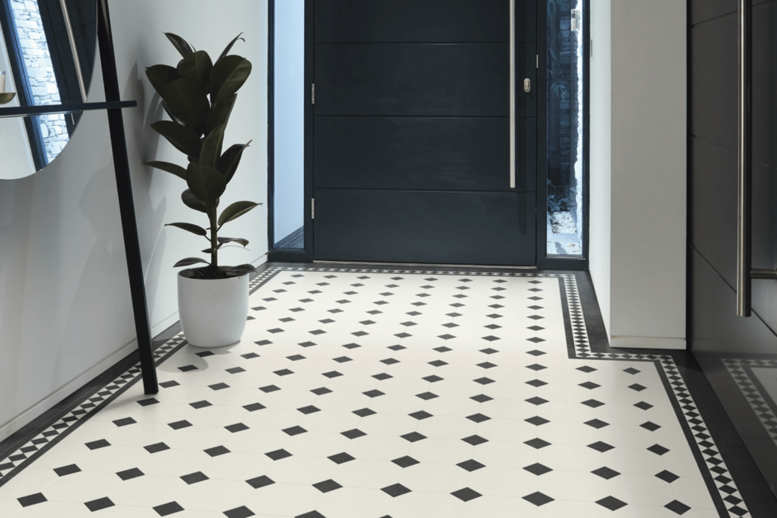Sol PVC à motif graphique noir et blanc dans une entrée moderne, avec porte sombre et plante en pot.